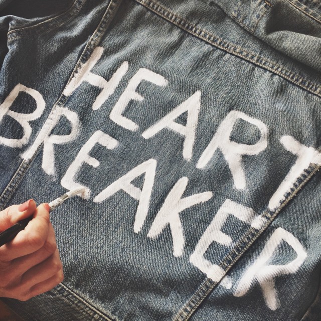 The words “Heart Breaker” are painted in white on a jean jacket or jean pants.